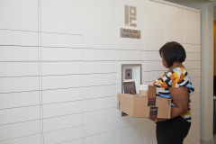 Woman retrieving package from smart apartment lockers Woman retrieving package from smart apartment lockers