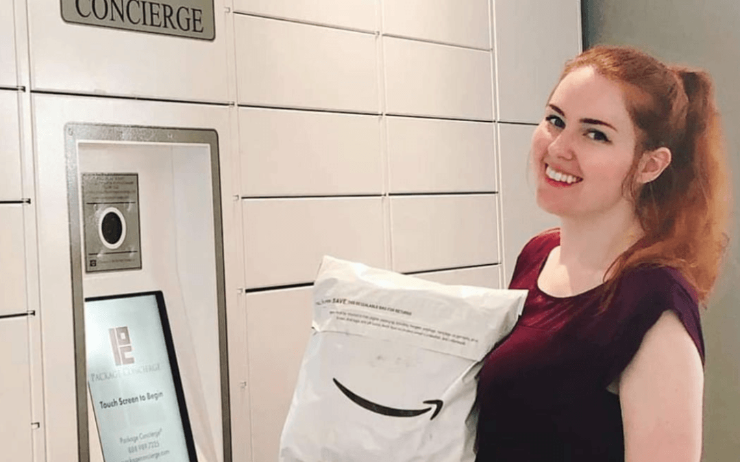 A woman in a maroon shirt is holding an Amazon package in front of a Package Concierge® smart electronic parcel locker