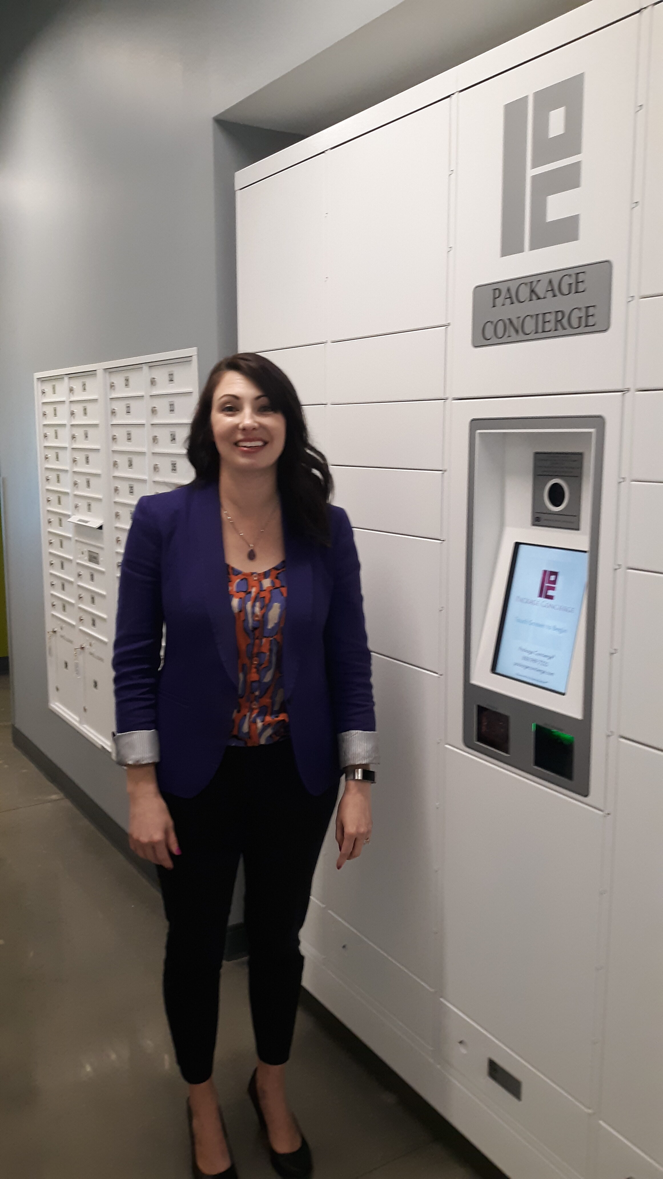 smiling woman in front of smart package locker and centralized mailbox